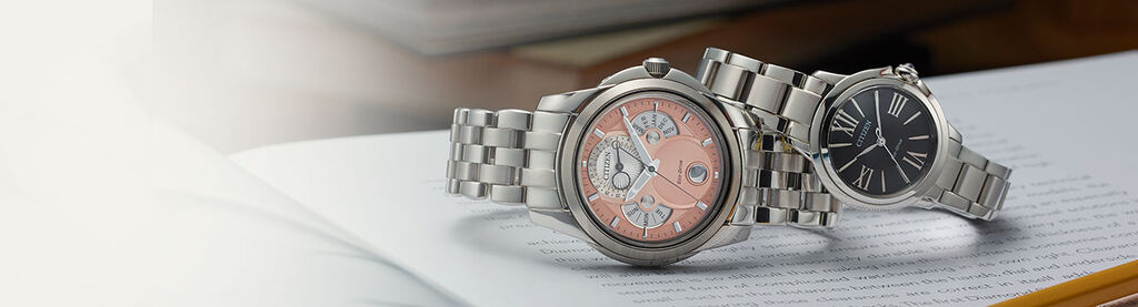 Graduation Watch Gifts; Featuring Calendrier watch model BU0080-52X and Ceci watch model EM1160-58E sitting on top of a book