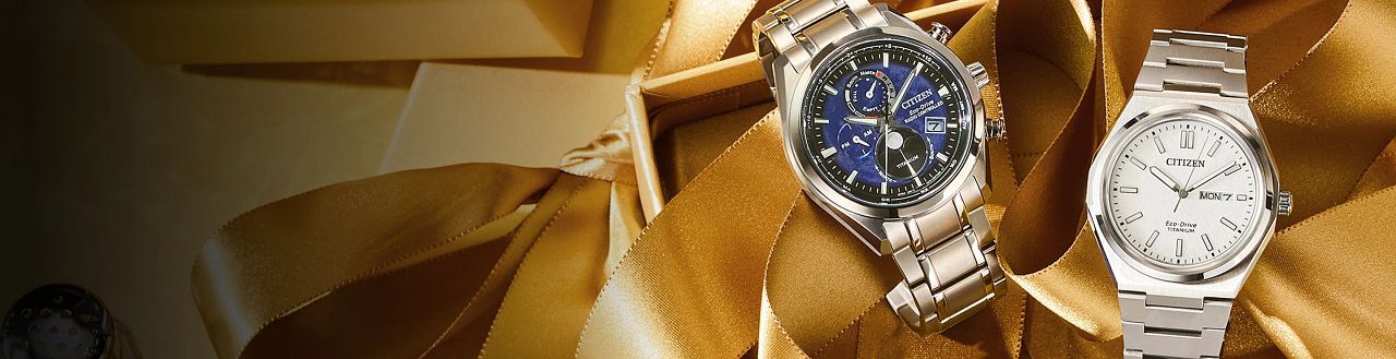 Images of two watches on top of gold holiday ribbon. Featuring Tsuki-yomi A-T watch model BY1010-57L and Zenshin Three-hand watch model AW0130-85A