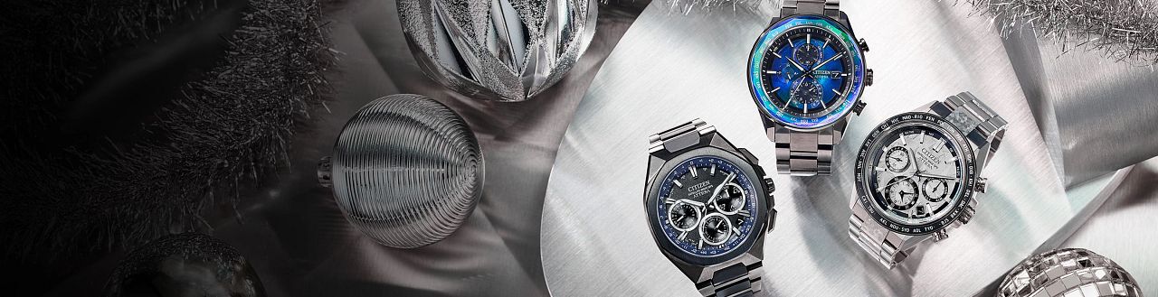 Luxury Gifts; Featuring an image of three ATTESA watch models on a silver background with holiday ornaments. Featuring ATTESA models CC4076-65A, AT8314-53L and CC4106-74E